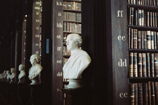 “Classical library interior with marble busts and antique books, symbolizing the evolution of knowledge from Aristotle to modern research.”