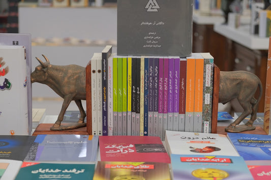 "Bookshelf with colorful books and bull-shaped bookends in a bookstore, showcasing diverse literature and reading collections."