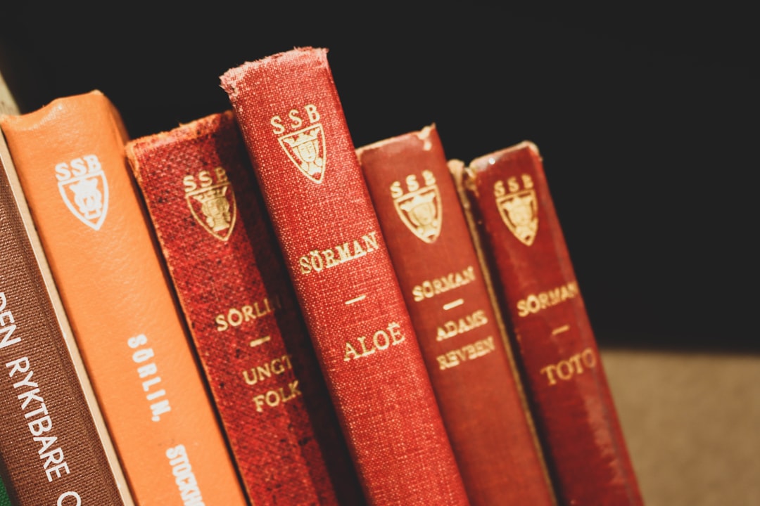 All visible spines (red and orange) feature an identical gold/light-colored emblem near the top, which consists of a shield with a crown or crest above it, and the letters "SSB" (or possibly "SBB") visible around or within the emblem.